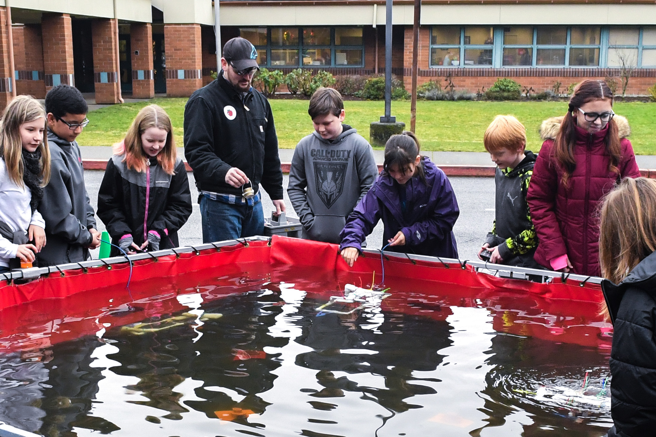 Elementary students testing the underwater ROVs they built in a pool.